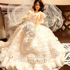 a crocheted wedding dress and veil is displayed on a doll's bed