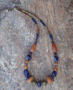 This necklace is subtle yet colorful.  Combines one large vintage African bead, two large vintage carnelian beads, orange sodalite beads, orange fire agate beads, and brass beads.  Also features a hook clasp.  The necklace is 17 inches long. Boho Jewelry Diy, Large Bead Necklace, Cowgirl Bling, Beaded Jewelry Necklaces, Stone Beaded Necklace, Carnelian Beads, Fire Agate, African Beads, Agate Necklace