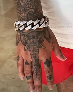 a man with tattoos on his arm and hand wearing a chain around his wrist that has an elephant on it