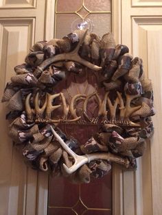 a wreath made out of antlers and burlocks hangs on the front door