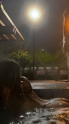 a woman sitting in a hot tub at night