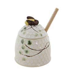 a ceramic honey jar with a wooden stick sticking out of it