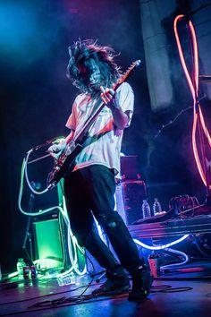 a man with long hair standing on stage playing an electric guitar and singing into a microphone