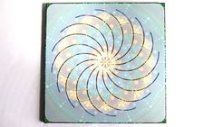 a square coaster with an abstract design on the front and back cover in blue, yellow and green