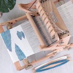 an old weaving machine is sitting on the floor next to some needles and yarns