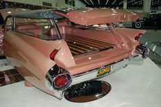 an old pink car is on display in a showroom