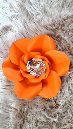 an orange flower is laying on some fur