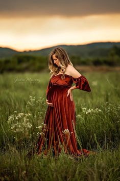 a woman in a red dress standing in tall grass