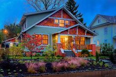 a large house with many windows and plants in the front yard at night, lit up by street lights