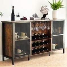 a cabinet with wine glasses, plates and cups on it next to a potted plant