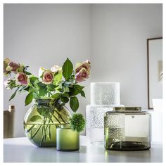 three vases with flowers in them sitting on a table next to candles and a mirror