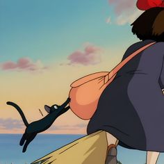 a woman with a cat on her back looking out at the ocean from behind her