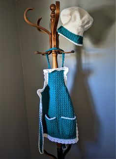 an old fashioned crocheted apron and hat on a wooden stand with a coat hanger