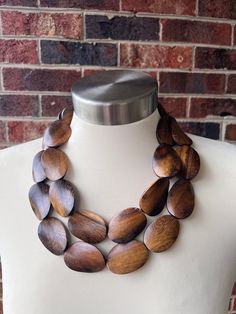 A chunky beaded multi strand statement necklace made with oval shaped brown wood beads. The color of the wood can vary from lighter to darker. Please let us know if you have a preference and we will try to accommodate it. - 3 strands - 1 and 2 strands also available - 1 strand has spacer beads which helps it lay flatter- Shortest strand measures 19-21" long (length will vary depending on the clasp)- Beads measure 1.5" by 1"- Sterling silver lobster claw clasp (stainless, gold stainless, gold fil Brown Beaded Necklace, Silver Jewelry Box, Pearl Statement Necklace, Photo Gold, Shepherds Hook, Necklace Chunky, Long Beaded Necklace, Wood Necklace, Beaded Statement Necklace