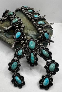 Vintage Antique Native American Solid Sterling Silver and Turquoise Squash Blossom Necklace. This vintage necklace is estimated to be from the 1930's or 1940's. There is no hallmark, tests as sterling silver. This necklace consists of sterling beads on a silver braided chain with simple hook clasp. Main pendant has 8 turquoise cabochon stones, 10 squash blossom beads on strand. Necklace is 24" inches in length and weighs 199 grams. Excellent condition; scuffs and scratches from wear, nice tarnish. Turquoise stones are rutilated and some have deep natural cracks, please see pictures. A stunning original Native American squash blossom necklace to add to your collection of fine vintage jewelry. Thank you for looking! Prices on shop items are fair and reasonable, so all prices are firm.  No re Vintage Turquoise Necklace With Patina, Southwestern Concho Necklaces For Western Events, Vintage Concho Jewelry For Ranch, Vintage Blue Turquoise Necklace With Concho, Southwestern Turquoise Necklace, Southwestern Turquoise Necklace For Western-themed Events, Western Style Turquoise Necklace Collectible, Vintage Turquoise Necklace With Concho Detail, Southwestern Style Turquoise Necklace For Vintage Collection