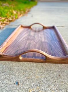 a wooden tray sitting on top of a cement floor next to grass and trees in the background