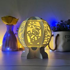 an illuminated lamp sitting on top of a wooden table next to a potted plant