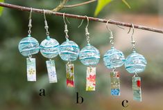 four glass beads hanging from a tree branch with letters on them and the letter abc