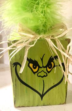 a potted plant with a face painted on it's side and green feathers