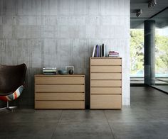 a room with a chair, bookshelf and two drawers