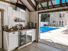 a kitchen with a pool in the back ground and an open door leading to it