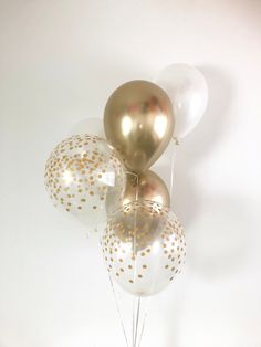 gold and white balloons in a vase on a table