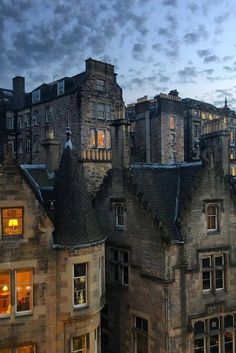 an old castle like building with many windows lit up in the evening sky and clouds