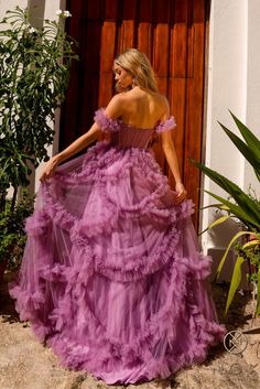 a woman in a long purple dress is standing by a door with her back to the camera