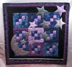 a quilted wall hanging with stars and moon on it