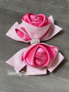 two pink roses with pearls on them sitting on top of a wooden table next to each other