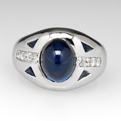 This charming ring is centered with one (1), bezel set, oval cabochon cut natural blue sapphire. The shoulders of the ring are each accented with two (2), flush set, triangle step cut natural blue sapphires and four (4), bead set, old European cut diamond. The ring measures 11.9mm at the top, rises 6.4mm above the finger, tapering to 2.8mm wide and 1.0mm thick at the base of the shank. The ring is currently a size 4.25 and we offer complimentary sizing to fit. Oval Sapphire Engagement Ring, Step Cut, Bead Set, Sapphire Diamond Ring, Engagement Rings Oval, European Cut Diamonds, Emerald Jewelry, Natural Blue Sapphire, Sapphire Engagement