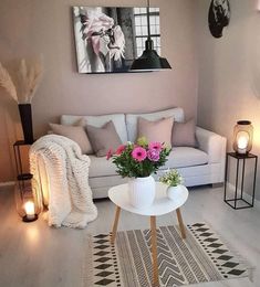 a living room filled with furniture and flowers on top of a white table in front of a painting