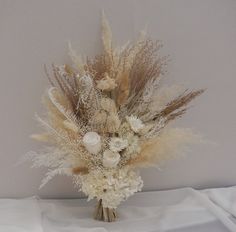 a vase filled with lots of flowers on top of a white cloth covered tablecloth