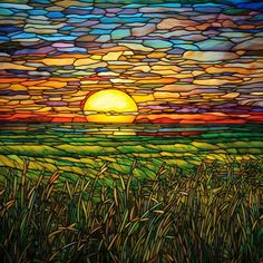 a stained glass window with the sun setting in the distance and grass on the ground