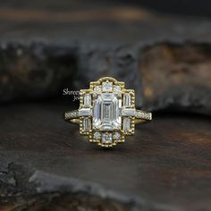 an emerald cut diamond ring sitting on top of a piece of wood