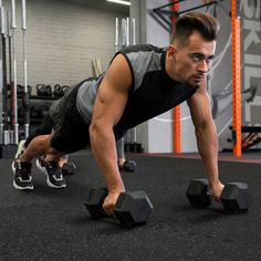 a man is doing push ups with two dumbbells in a crossfit gym