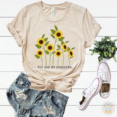 You are my sunshine T shirt, Sunflower T-shirt,Sunflower lover, Graphic Tee, Sunflower Tee,Inspirational Tee, Womens Floral Tee,Botanical Shirt,Garden shirt. This t-shirt is everything you've dreamed of and more. It feels soft and lightweight, with the right amount of stretch. It's comfortable and flattering for both men and women. * 100% combed and ring-spun cotton (Heather colors contain polyester) * Ash color is 99% combed and ring-spun cotton, 1% polyester * Heather colors are 52% combed and Cotton Crew Neck T-shirt With Sunflower Design, Summer Casual T-shirt With Sunflower Print, Yellow T-shirt With Sunflower Design For Spring, Relaxed Fit Sunflower Print Graphic Tee, Yellow T-shirt With Plant Print For Summer, Cotton T-shirt With Sunflower Design, Casual Sunflower Design T-shirt With Relaxed Fit, Relaxed Fit Short Sleeve T-shirt With Sunflower Design, Casual Sunflower Design T-shirt In Relaxed Fit