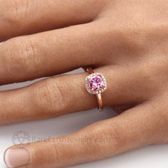 a woman's hand with a pink diamond ring on it