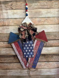 an american flag decoration hanging on a wooden wall next to a red, white and blue ribbon