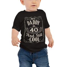 "Celebrate dad's milestone birthday in style with this adorable baby t-shirt. Featuring a vintage-inspired print that reads \"My Daddy Is 40 And Still Cool,\" this shirt is the perfect way to show off dad's hip and trendy side, even as he enters his 40s. Made with soft and comfortable materials, this shirt is perfect for keeping your little one cozy and cute, while showing off your family pride. Whether you're at a family gathering or out running errands, this shirt is sure to bring a smile to e Retro Cotton T-shirt For Father's Day, Retro Letter Print Tops For Father's Day, Vintage Short Sleeve T-shirt For Father's Day, Retro Graphic Print T-shirt For Father's Day, Vintage Black Top Gift, Vintage Black Top As Gift, Black Vintage Top Gift, Vintage T-shirt For Father's Day Anniversary, Vintage Letter Print T-shirt For Father's Day