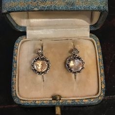 These antique earrings have elements from two different periods (and centuries!)--Georgian and Victorian.  Set in late 19th Century mountings of platinum and 14k yellow gold are two 18th Century closed foil-backed rose cut diamonds in their original silver settings.  The diamonds, still in great condition considering their age, have a warm, candlelight-like hue to them which is due both to their natural color and to the foil-backing.  Set in the top of the mounting are also two additional tiny r Victorian Gold Diamond Earrings With Brilliant Cut, Victorian Round Diamond Earrings, Victorian Brilliant Cut Diamond Earrings, Ornate Historical Drop Earrings, Georgian Earrings, 19th Century Women, Victorian Earrings, Vintage Jewlery, Diamond Birthstone