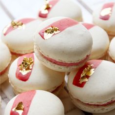 some white and pink macaroons with gold decorations on them