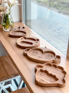 three wooden trays sitting on top of a table next to a vase with flowers