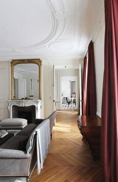 a living room filled with furniture and a large mirror on the wall next to it