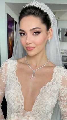 a woman in a wedding dress with a veil on her head and wearing a tiara