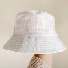 a white brimmed hat with the word bride on it is held by a woman's hand