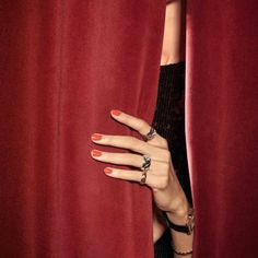 a woman's hand peeking out from behind a red curtain