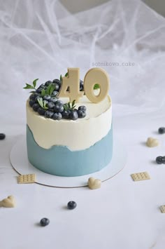 a birthday cake with blueberries and greenery on top