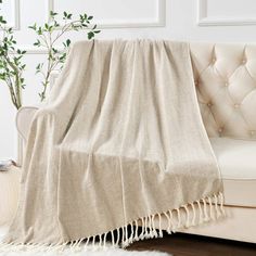 a couch with a white blanket on top of it next to a potted plant