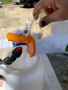 someone is filling up a plastic jug with water and an orange handled toothbrushes